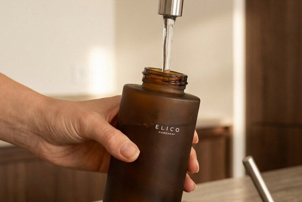 A hand fills an amber bottle with tap water