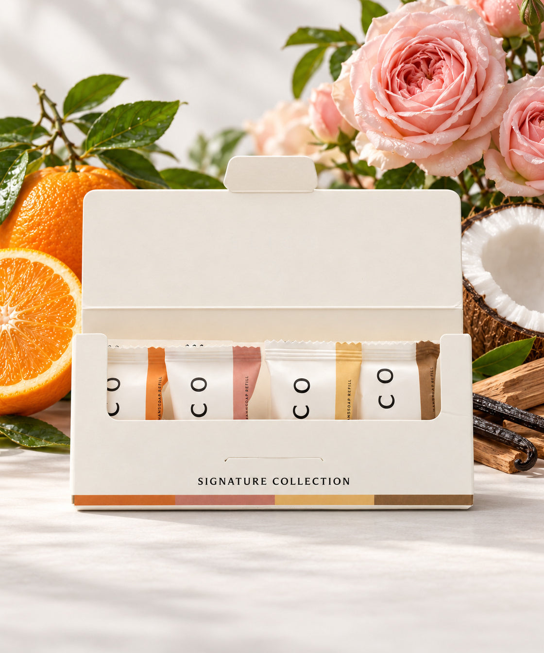 Elico handtvål refills 4-pack Signature Collection, en av varje doft, öppen kartong framför apelsin, rosor, kokos och sandelträ